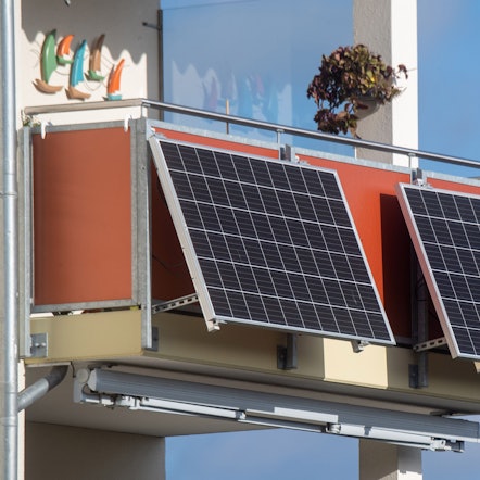 Solarmodule für ein sogenanntes Balkonkraftwerk hängen an einem Balkon.