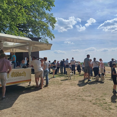 Leute stehen am Rande eines Reiturnierplatzes.