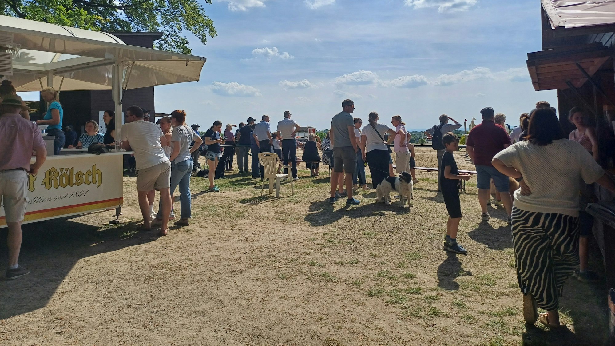 Leute stehen am Rande eines Reiturnierplatzes.