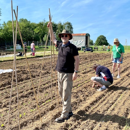 Zu sehen ist Elmar Oberdörffer, der Bambusstäbe in die Erde steckt.