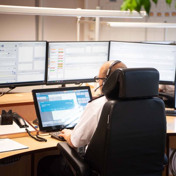 Das Bild zeigt einen Disponenten in der Leitstelle, der vor zahlreichen Monitoren sitzt.