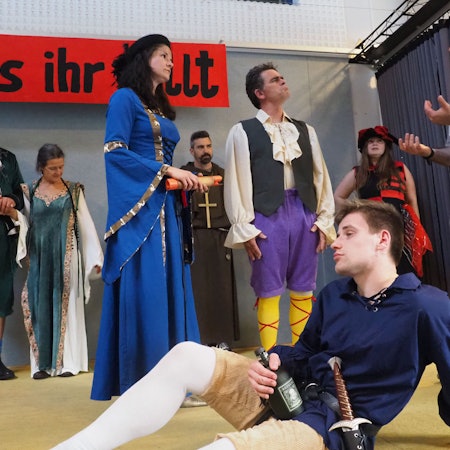 Jonas Kuley sitzt im Vordergrund, dahinter agieren mehrere Schauspieler.