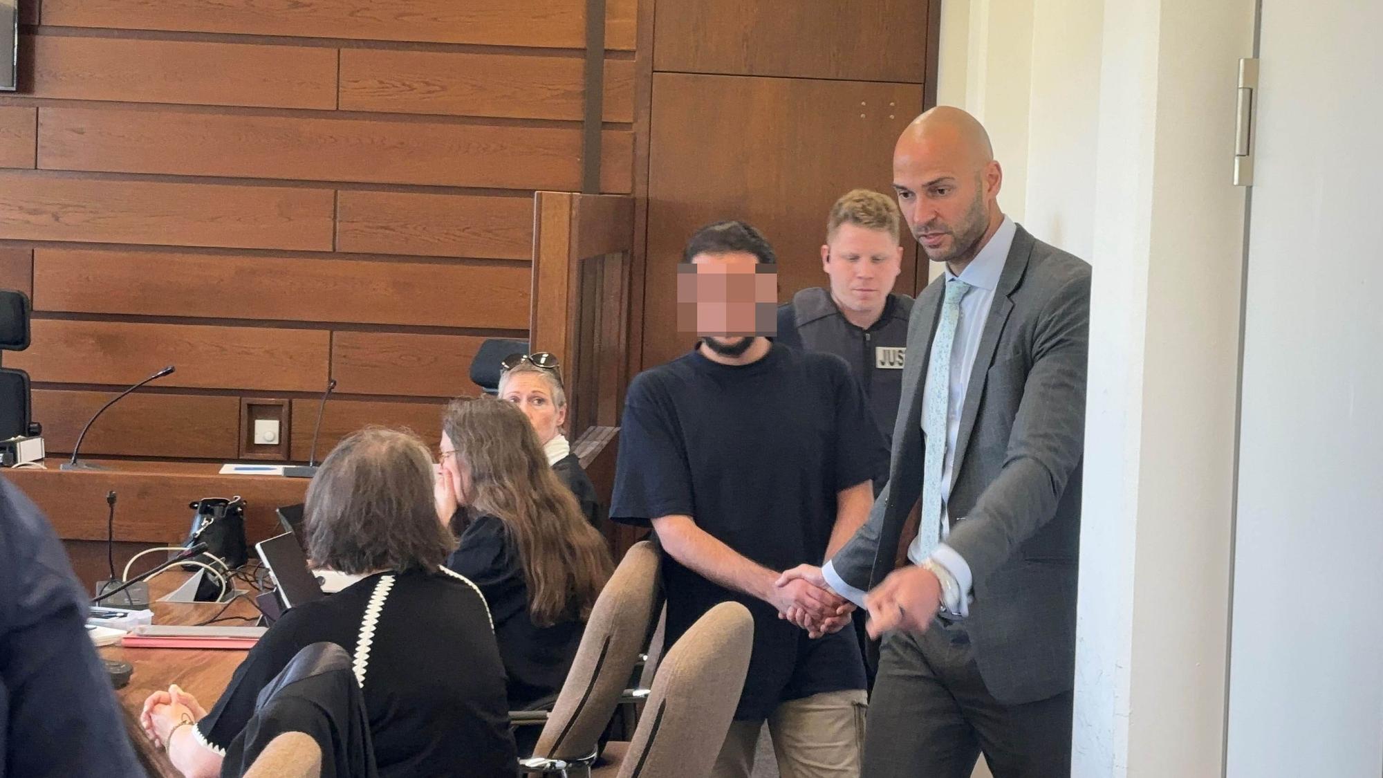 Das Bild zeigt, wie ein junger Mann in den Gerichtssaal geführt wird.
