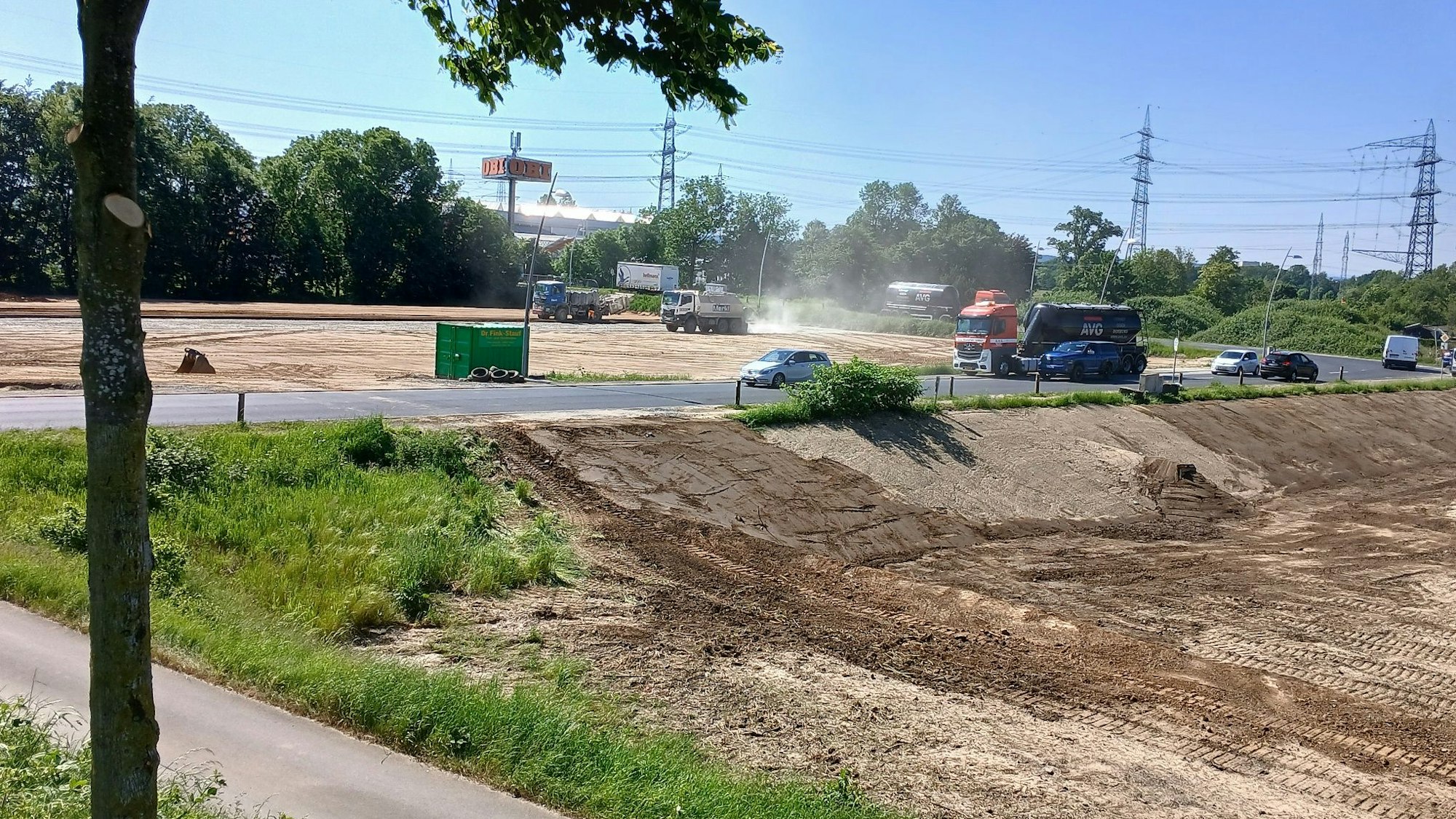 Erdarbeiten mit schweren Fahrzeugen auf zwei durch eine Straße getrennten Grundstücken.