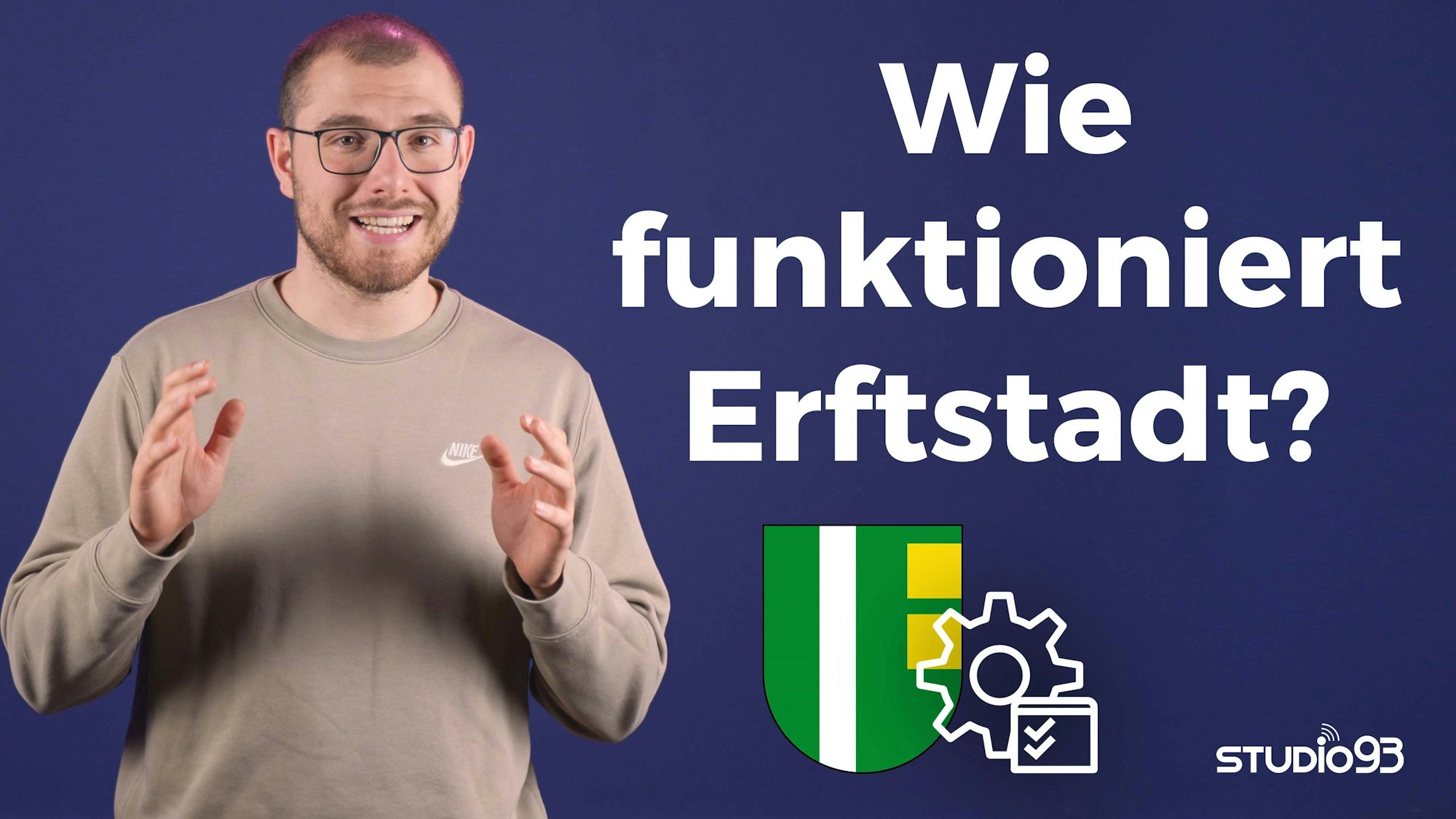 Ein Mann steht vor einem dunkelblauen Hintergrund.