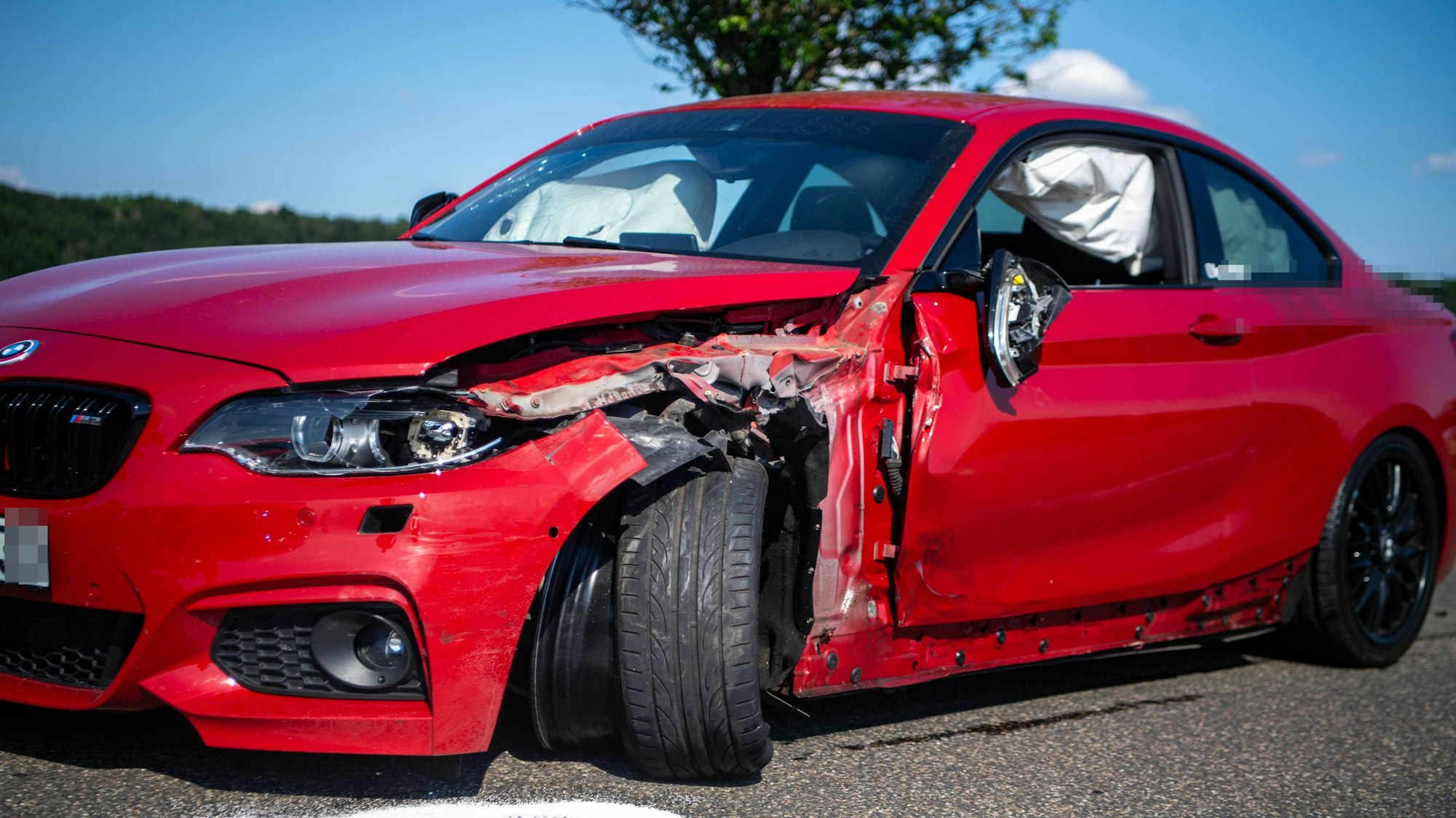 Das Bild zeigt den roten BMW M2, der mit dem Krad kollidiert ist. Er ist an der Fahrerseite beschädigt.
