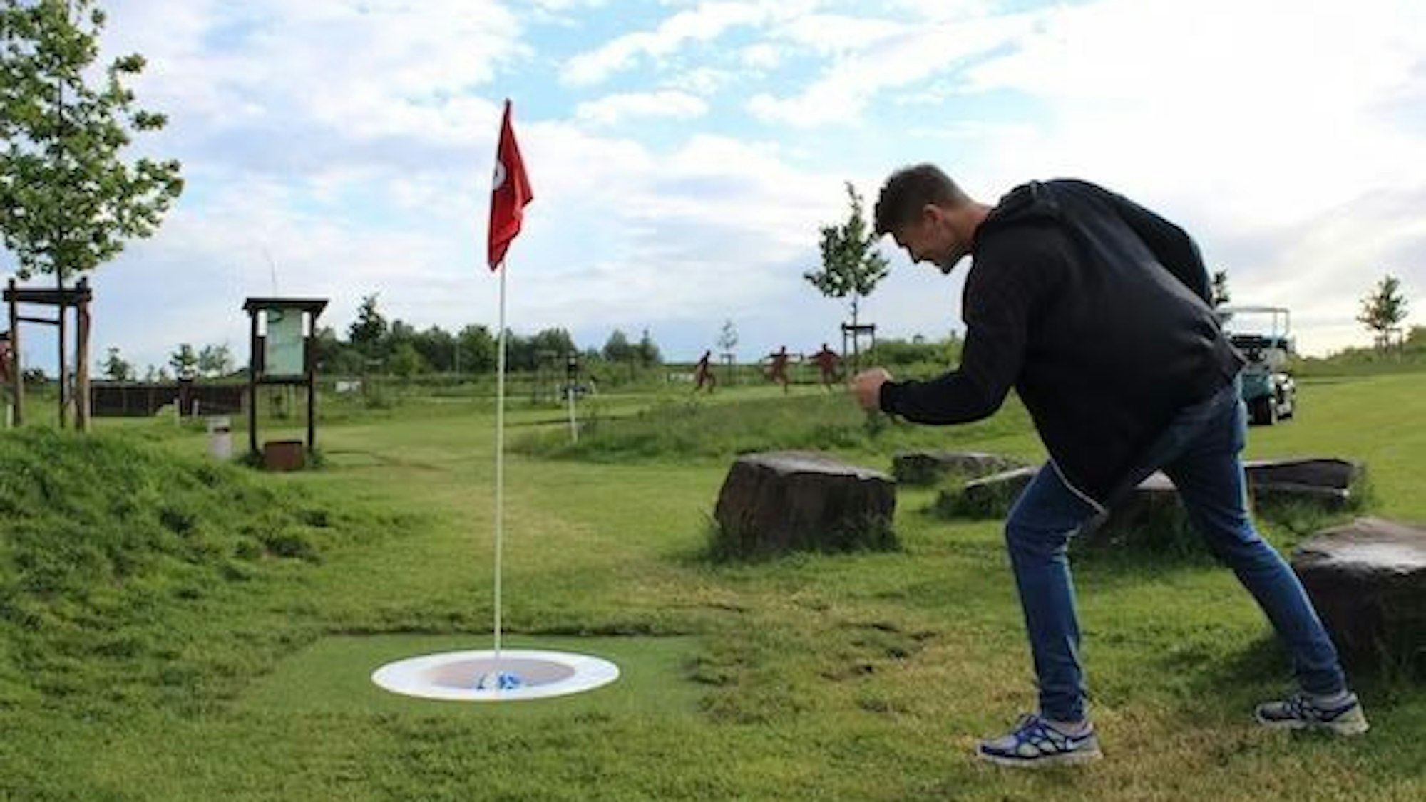 Ein Mann freut sich über einen im Loch versenkten Fußball.