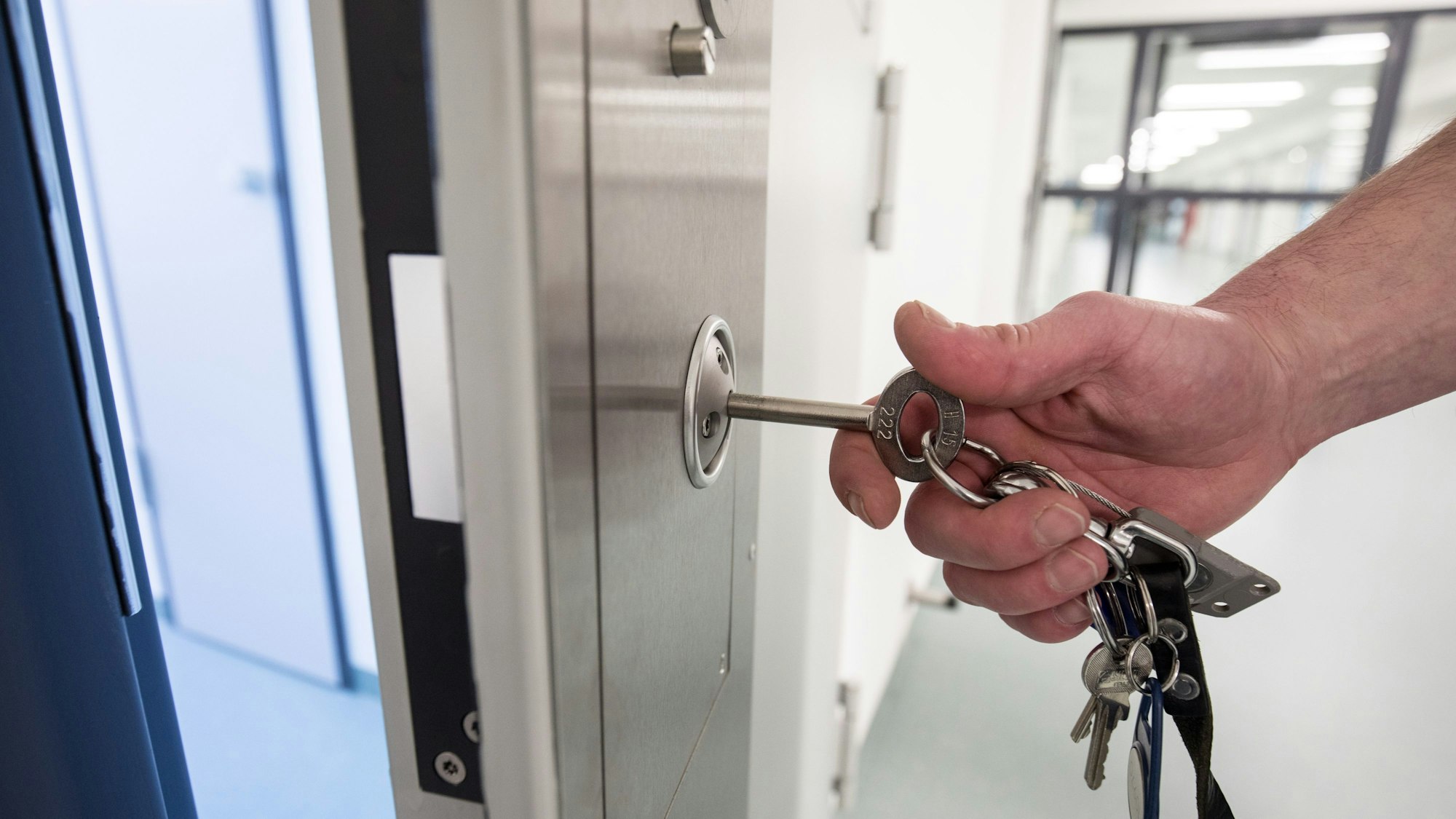 Das Bild zeigt einen Justizbeamten, der eine Zellentüre aufschließt.