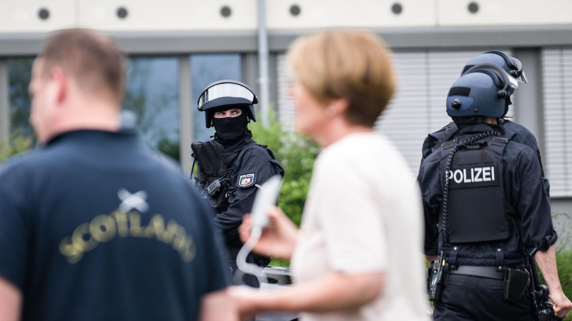 Einsatzkräfte mit schweren Waffen neben Zivilpersonen an der Schule in Wachtberg.