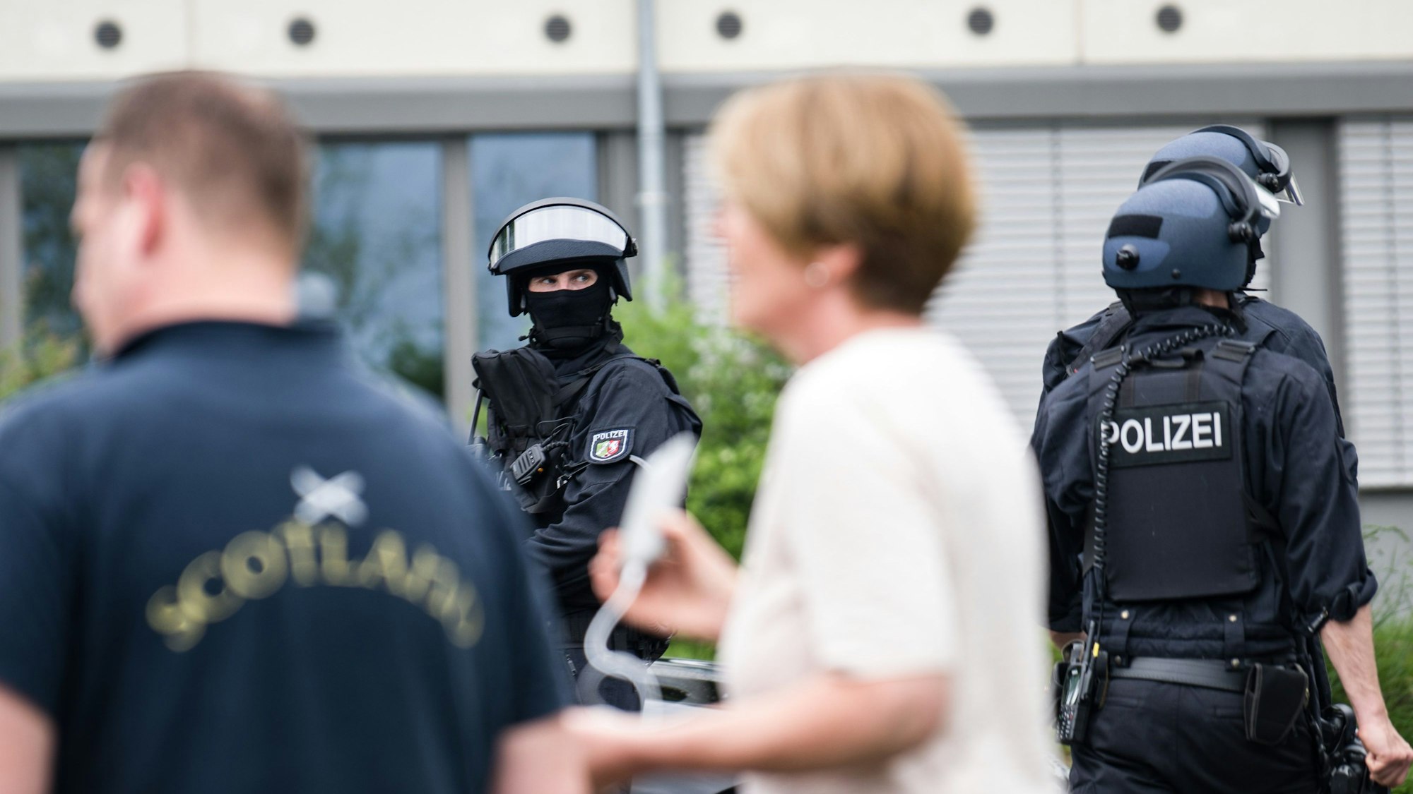 Einsatzkräfte mit schweren Waffen neben Zivilpersonen an der Schule in Wachtberg.