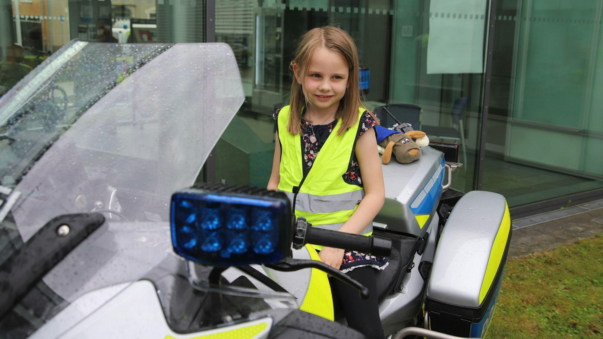 Ein Mädchen sitzt auf dem Sitz eines Polizeimotorrades.