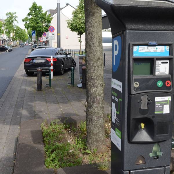 Parkscheinautomat an einer Straße. An der Seite ein weißes P auf blauem Grund, an der Front ein LCD-Display und farbige Knöpfe.