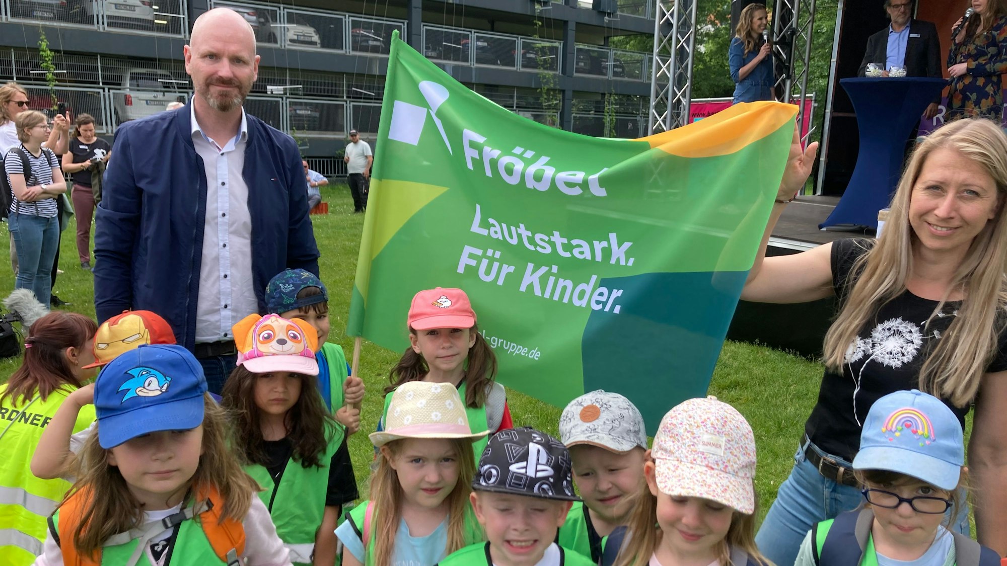 Kita-Demo in Düsseldorf: Arnd Kortwig ist mit einem Demo-Banner zu sehen. Vor ihm und einer Mitdemonstrantin stehen Kinder im Kita-Alter.