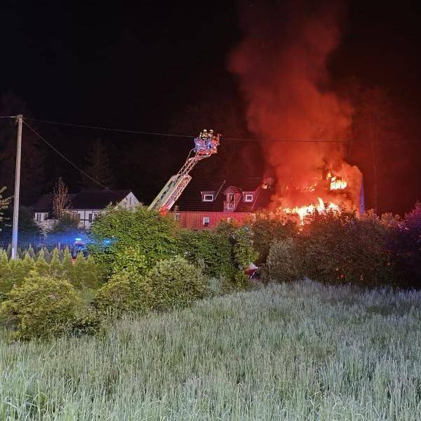 Ein Haus steht lichterloh in Flammen, die Feuerwehr löscht unter anderem mit Hilfe einer Drehleiter.