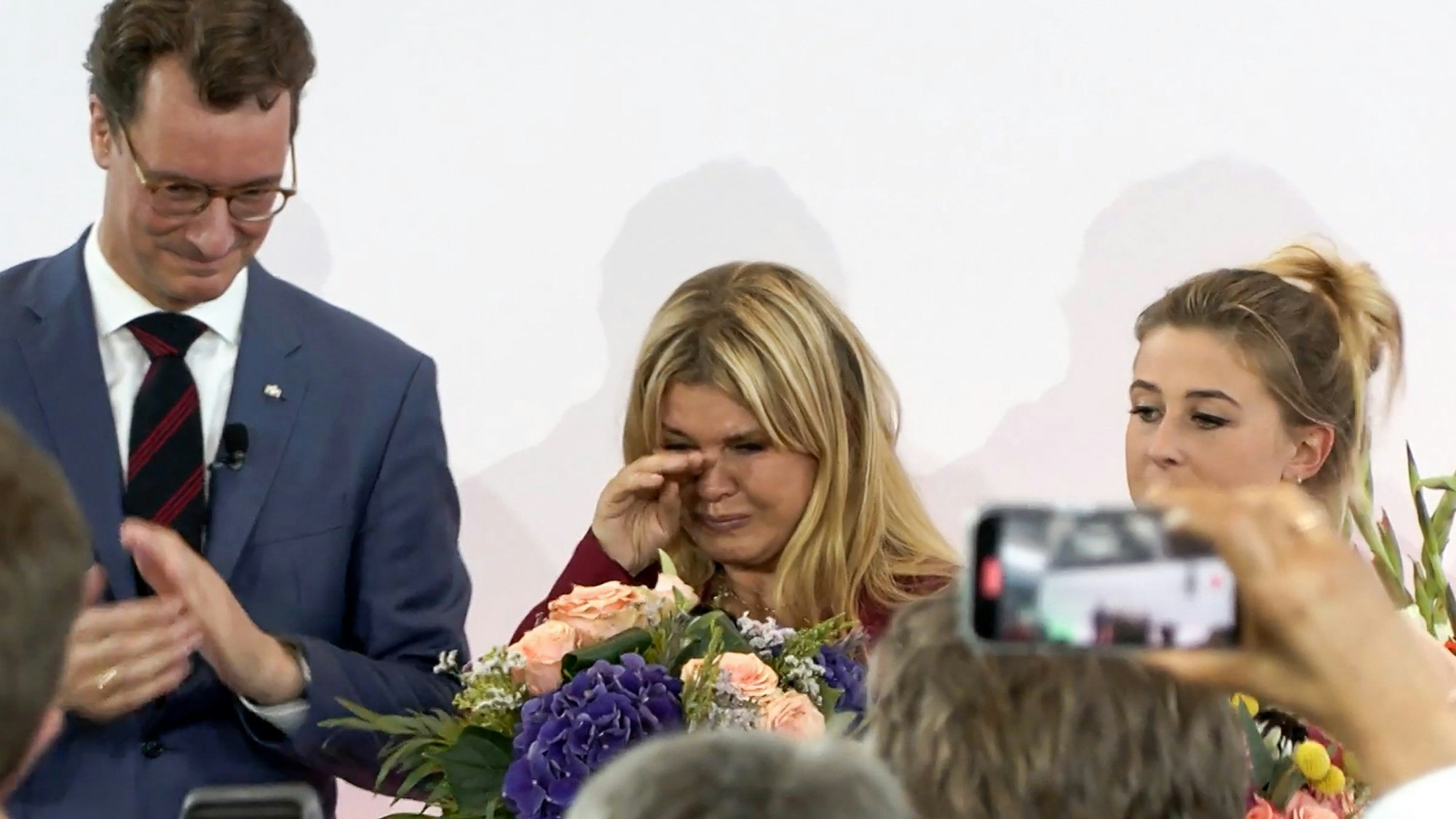 Hendrik Wüst (CDU, l-r), Ministerpräsident von Nordrhein-Westfalen, übergibt die Auszeichnung für Michael Schumacher an dessen Frau Corinna Schumacher und dessen Tochter Gina.