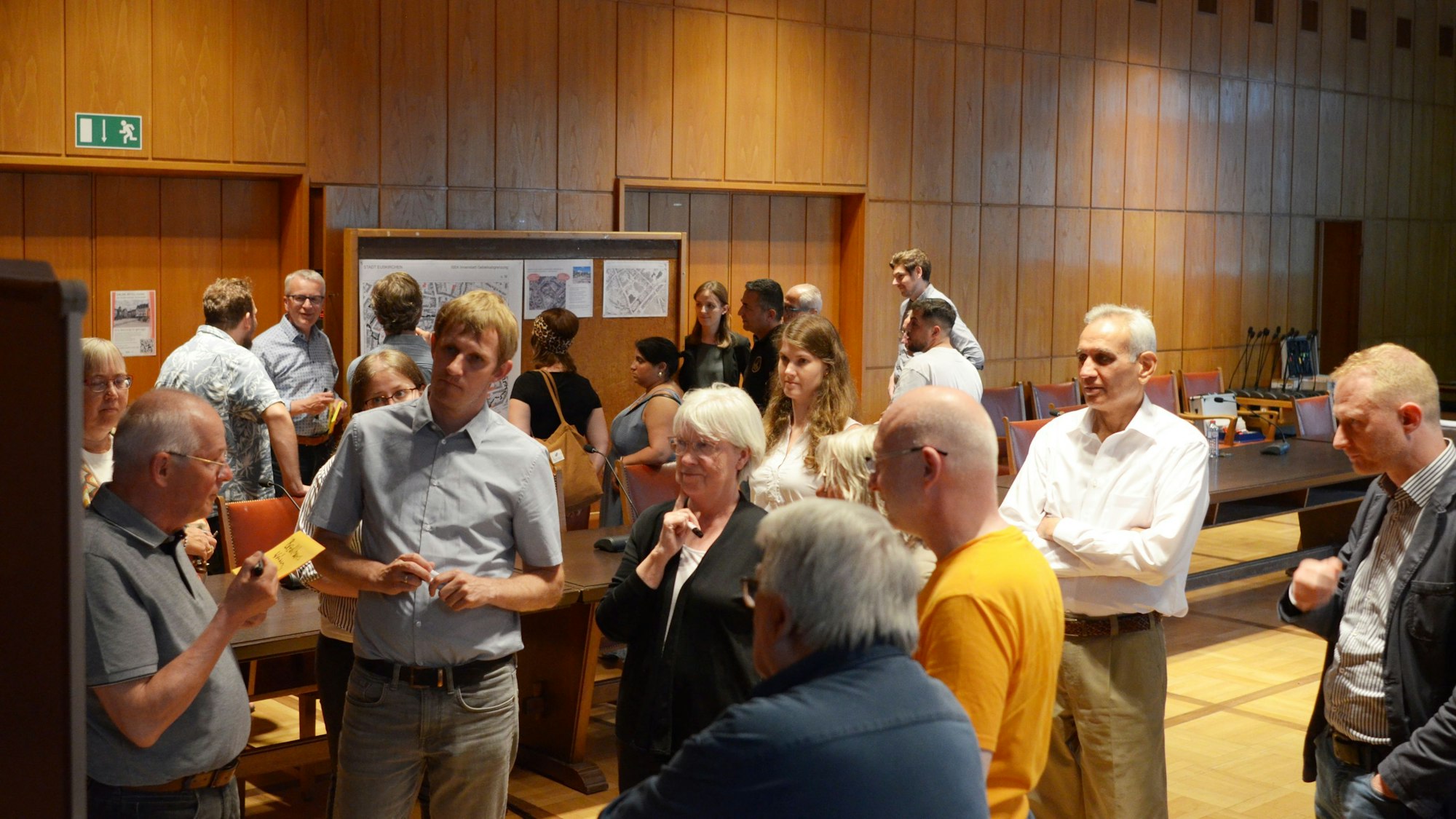 Frauen und Männer stehen diskutierend in Gruppen zusammen.