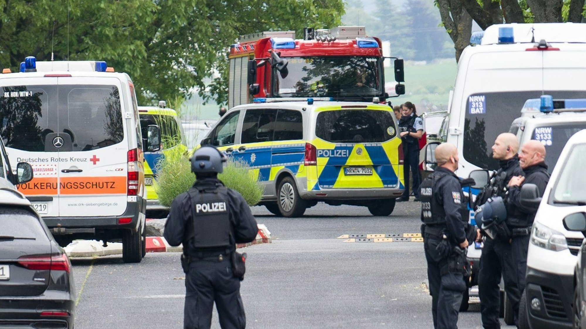 Ein Aufgebot von Polizeikräften ist an einer Schule in Wachtberg im Einsatz. Zudem sei es an einer benachbarten Asylunterkunft zu einem Messerangriff gekommen.