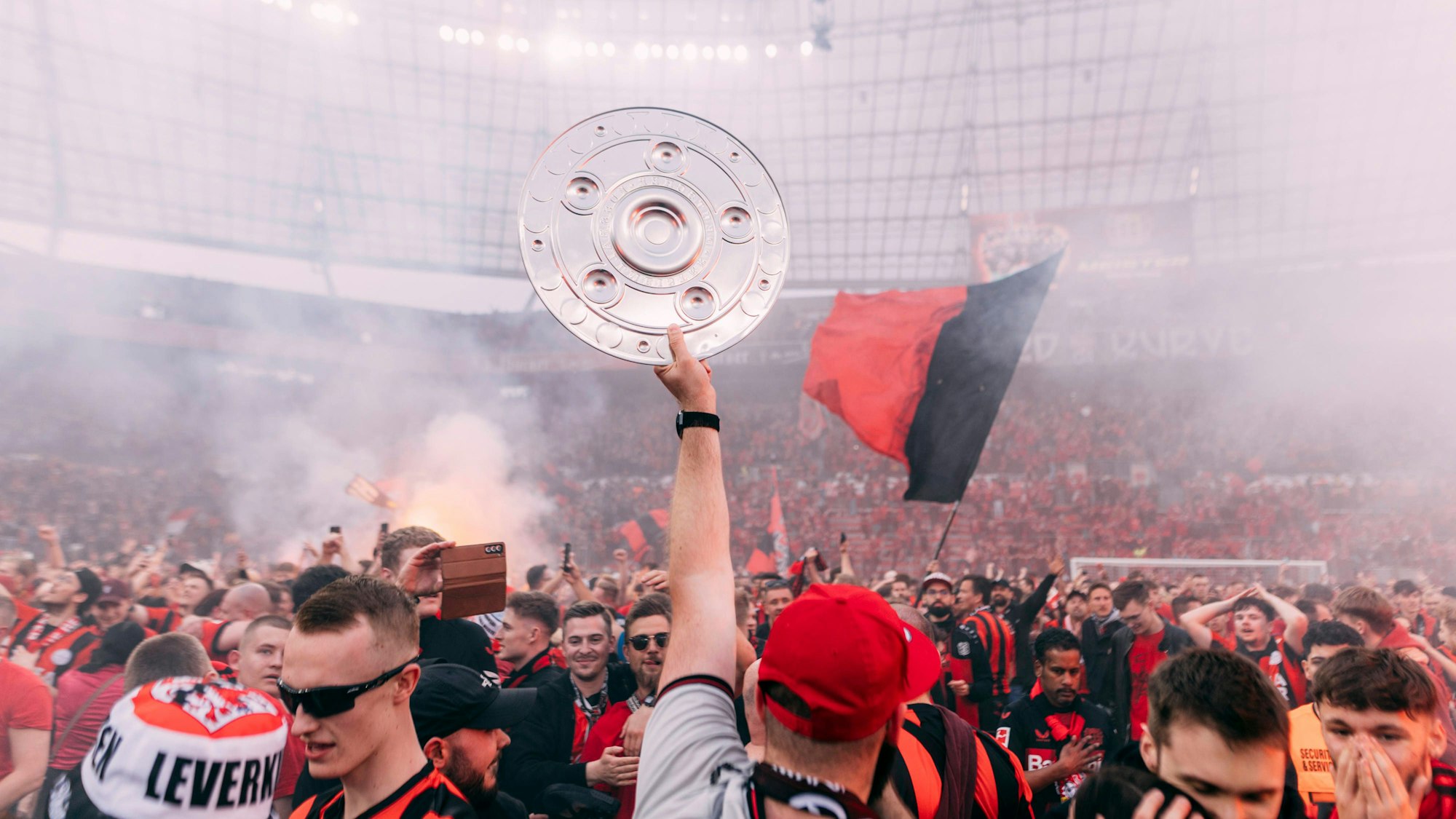 Leverkusen, Bayarena, 14.04.2024: Platzsturm der Leverkusener Fans bei der Meisterschaftsfeier beim Spiel der 1.Bundesliga Bayer 04 Leverkusen vs. Werder Bremen. Ein Fan streckt eine Replik der Meisterschale in den Himmel.