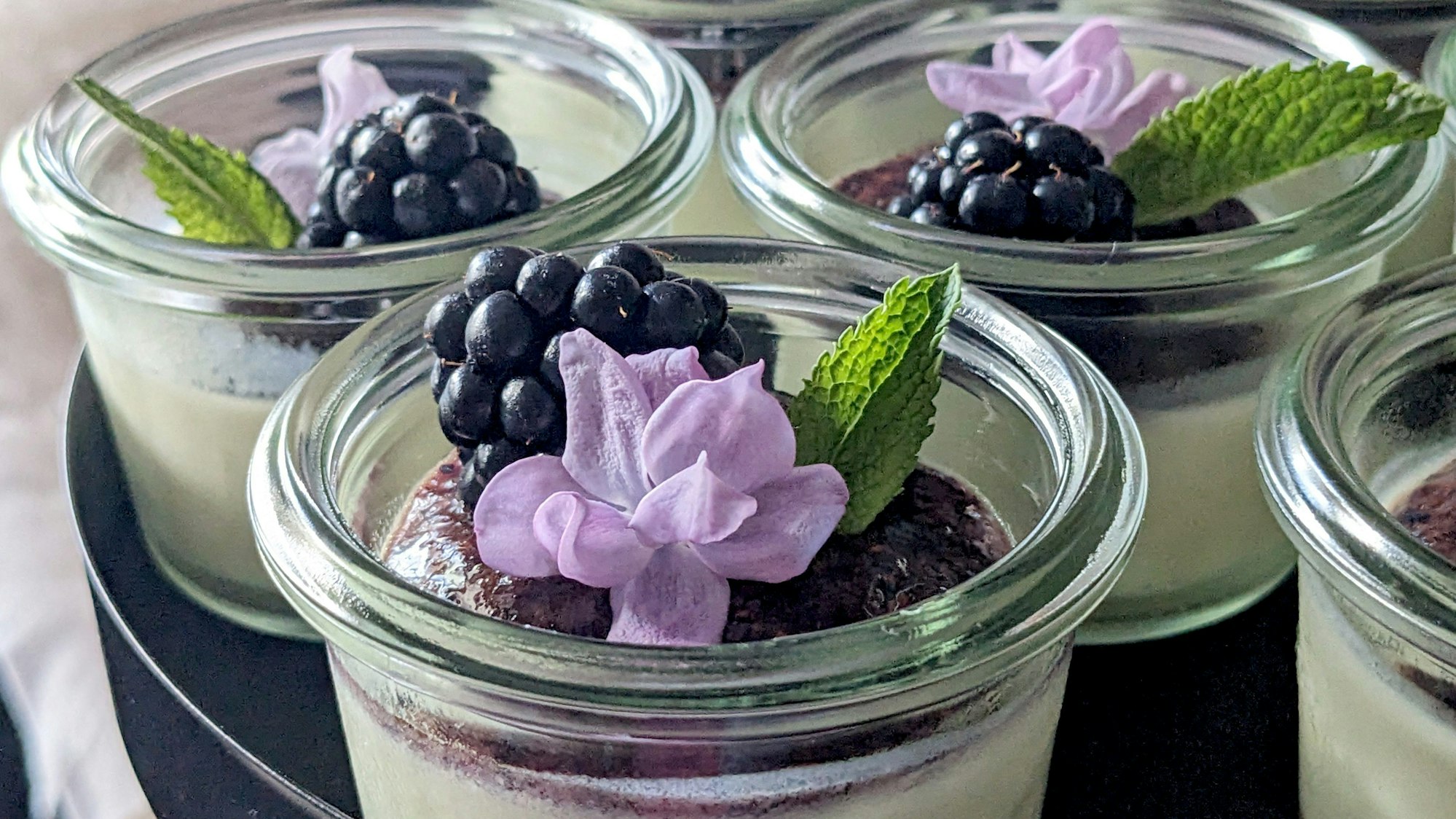 Die Panna Cotta ist in kleinen Gläsern angerichtet und mit Veilchenblüten verziert.