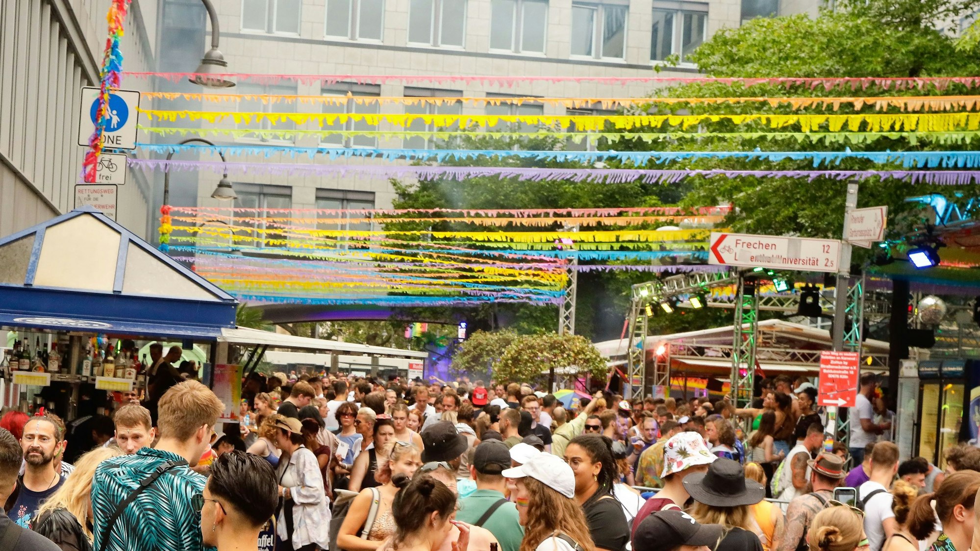 Das Bild zeigt eine Menschenmenge auf der Schaafenstraße unter Girlanden in Regenbogenfarben. (Symbolbild)