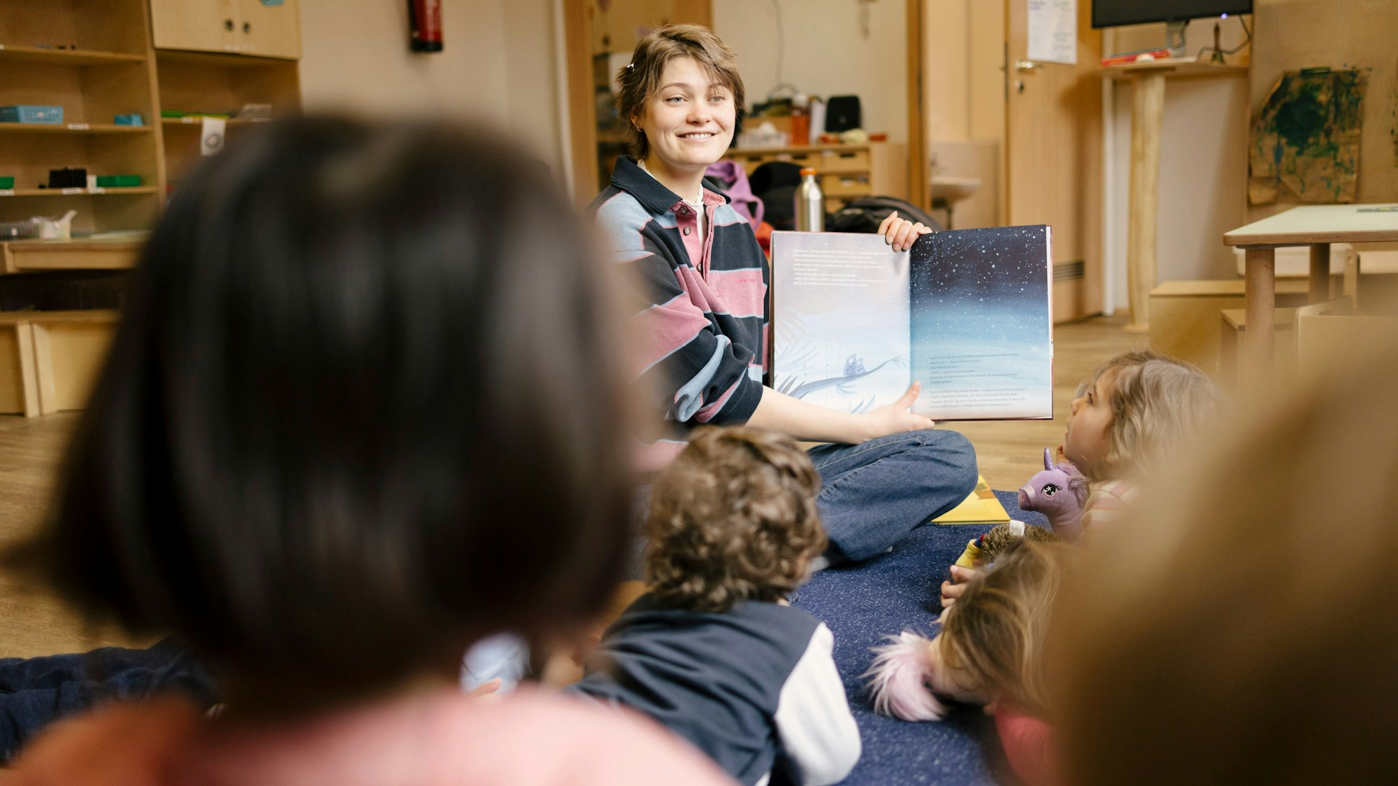 Eine ehrenamtliche Vorleserin der Initiative „Lesewelten“ liest Kindern vor.