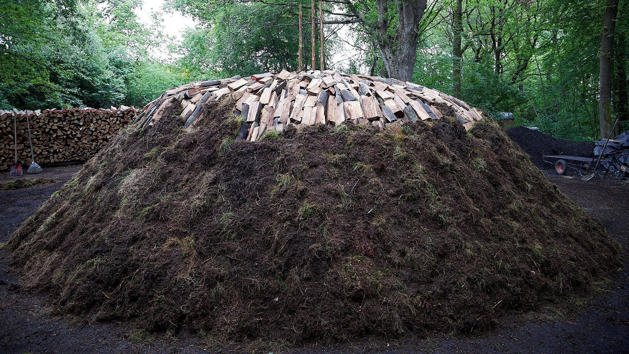 Der Düttlinger Kohlemeiler: Unten ist er mit Grassoden bedeckt, oben liegen die Holzscheite noch offen.