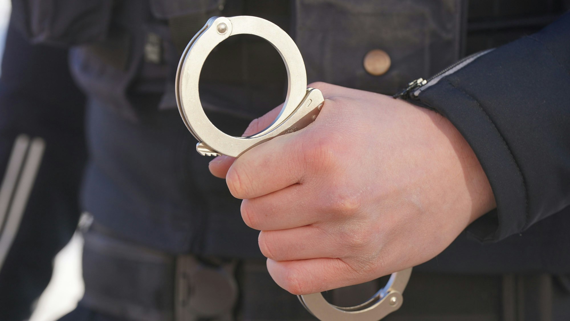 Ein Polizist hält Handschellen in der Hand.