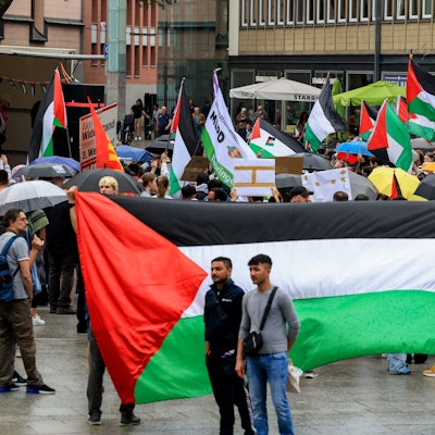 Menschen mit Palästina-Flaggen stehen auf dem Bahnhofsvorplatz in Köln.
