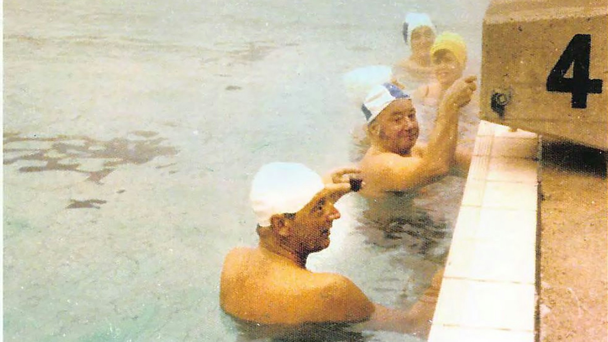 Altes Foto von Schwimmern in einem Schwimmbecken am Stein mit der Bahnnummer vier.