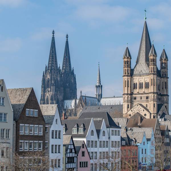 Blick auf die historische Skyline in der Kölner Altstadt. Im Vordergrund bunte Giebelhäuschen, im Hintergrund sind der Dom und Groß St. Martin zu sehen.