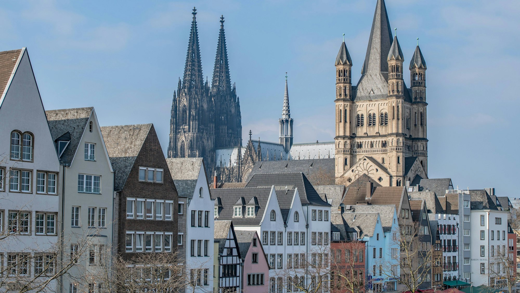 Blick auf die historische Skyline in der Kölner Altstadt. Im Vordergrund bunte Giebelhäuschen, im Hintergrund sind der Dom und Groß St. Martin zu sehen.