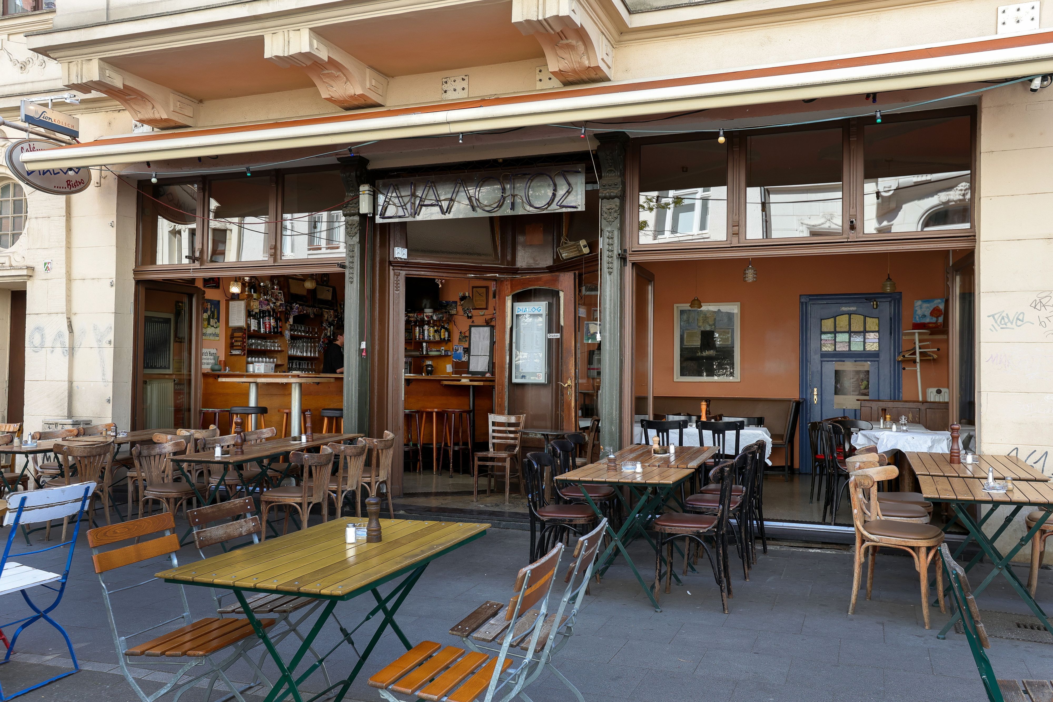 Das Restaurant „Dialog“ mit Holztischen- und Stühlen vor der Tür und innen.