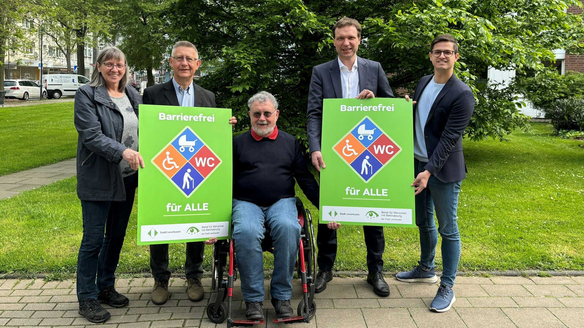 Eine Frau und vier Männer posieren mit Schildern für ein Foto.