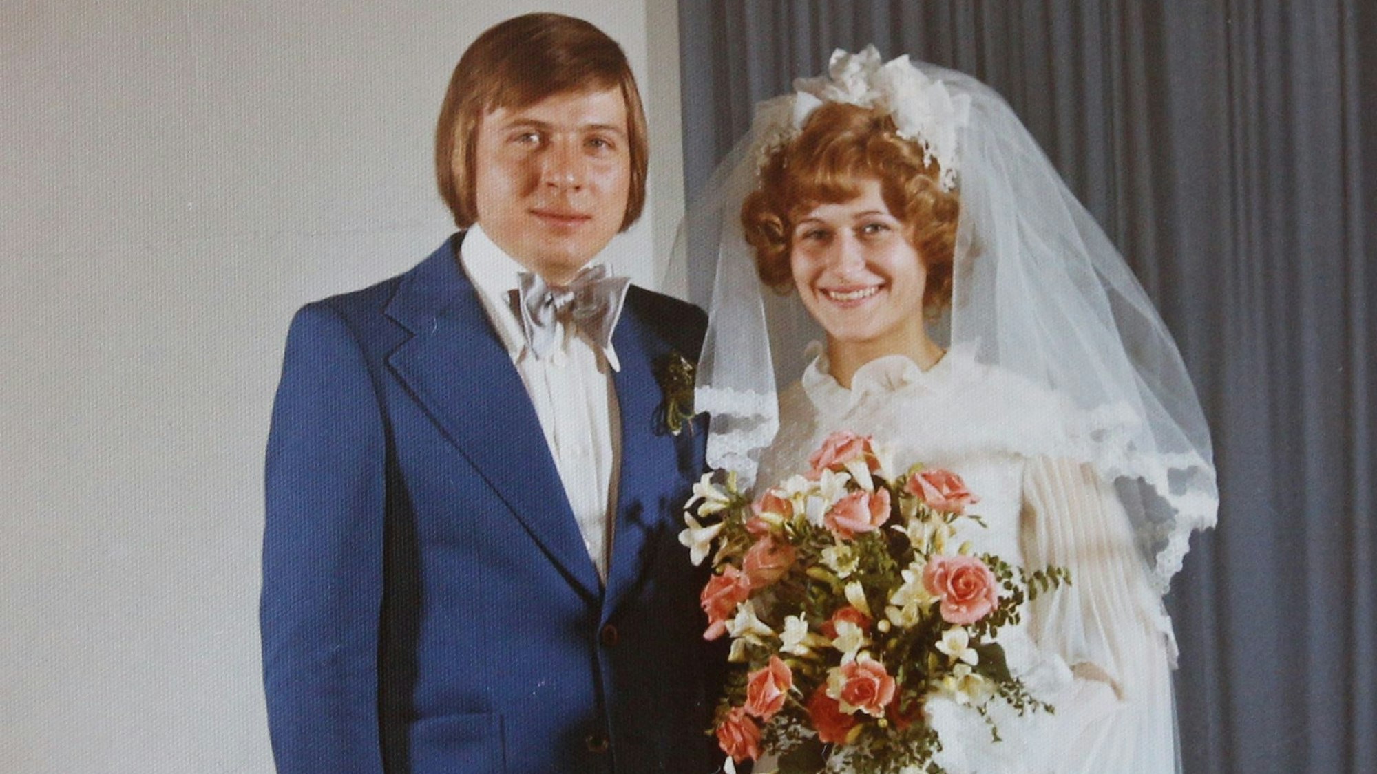 Die Braut im weißen Kleid, der Bräutigam im blauen Anzug mit Fliege.