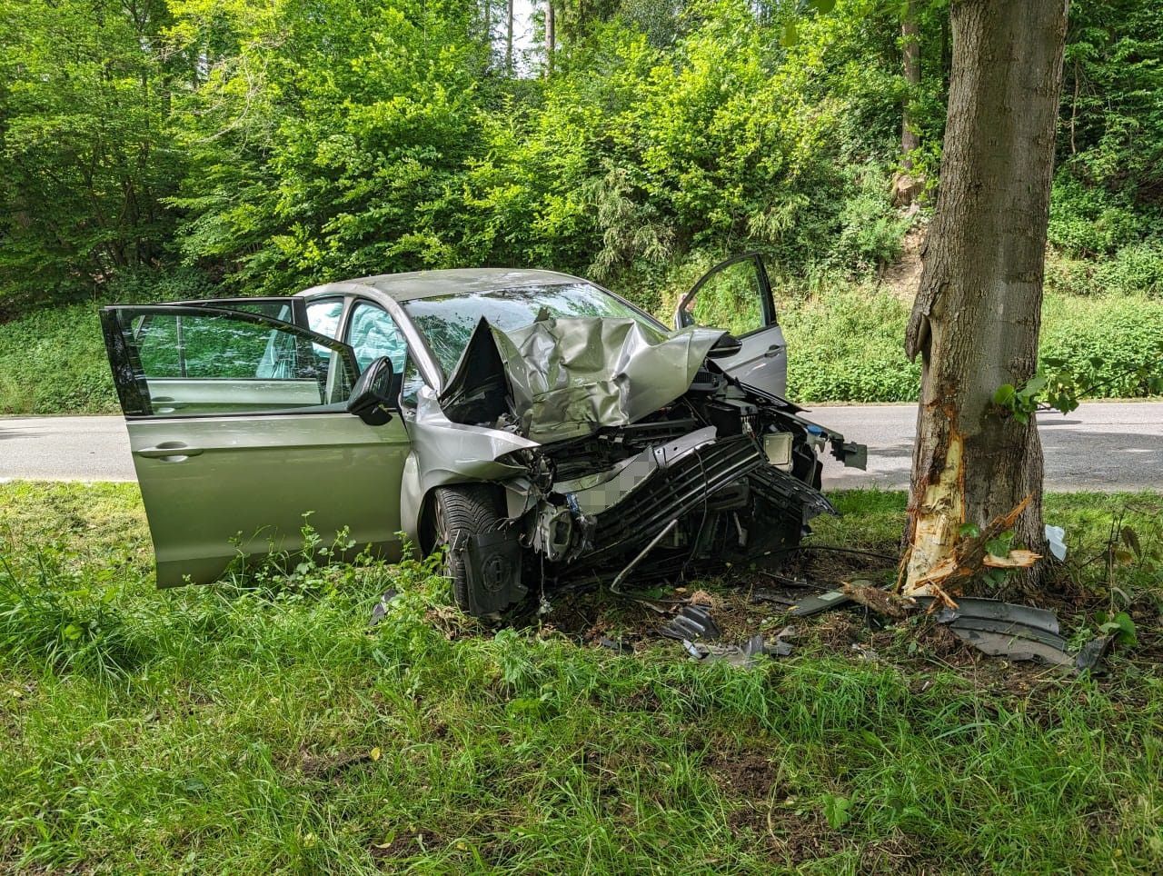 Ein zerstörtes Auto steht neben einem Baum.