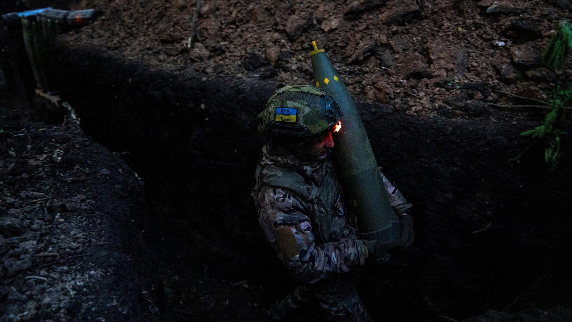 Ein ukrainischer Soldat der 148. separaten Artilleriebrigade der Luftangriffskräfte der Streitkräfte der Ukraine trägt eine Granate, während er sich mit Kameraden darauf vorbereitet, eine leichte Schlepphaubitze vom Typ M777 auf russische Stellungen abzufeuern. (Symbolbild)