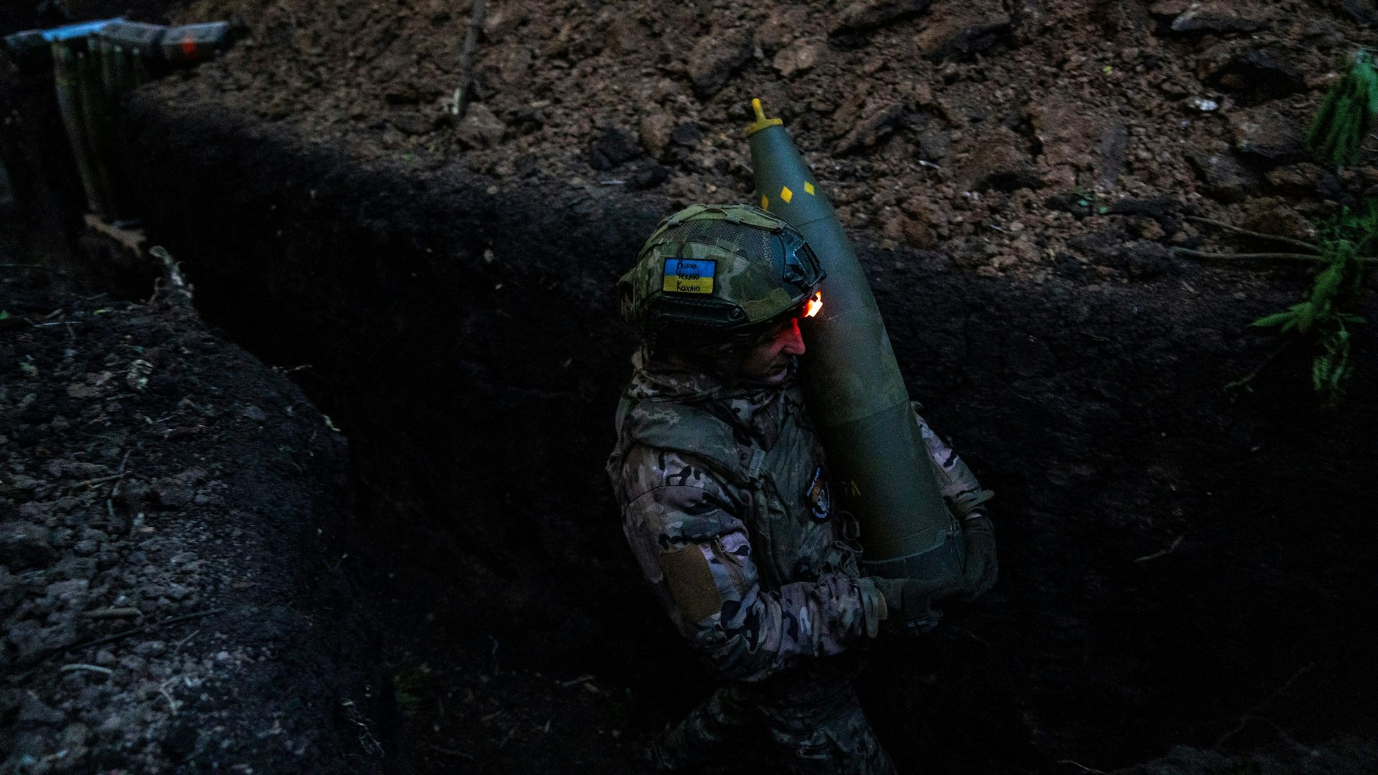 Ein ukrainischer Soldat der 148. separaten Artilleriebrigade der Luftangriffskräfte der Streitkräfte der Ukraine trägt eine Granate, während er sich mit Kameraden darauf vorbereitet, eine leichte Schlepphaubitze vom Typ M777 auf russische Stellungen abzufeuern. (Symbolbild)