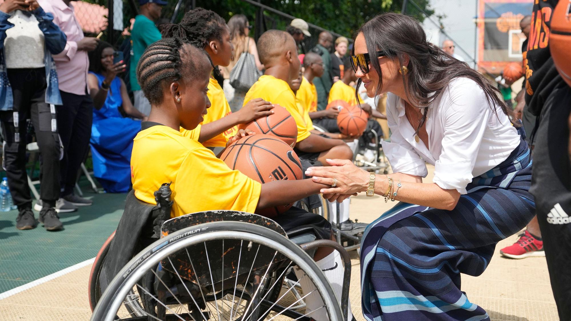 Meghan Markle (r) gibt einem Mädchen im Rollstuhl während der Giant of Africa Foundation in der Dream Big Basketball Klinik die Hand.
