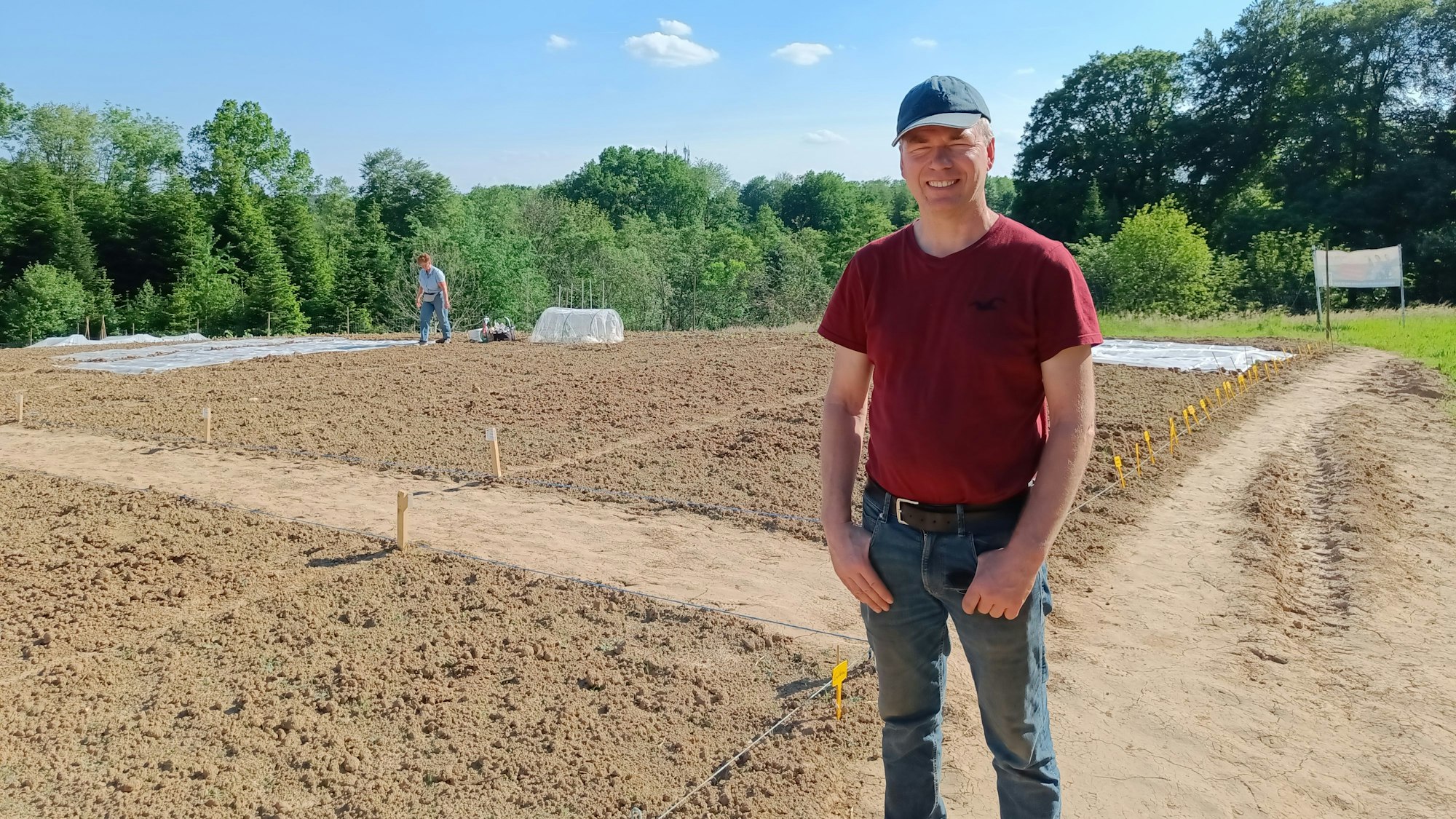 Ein Mann steht vor einem abgesteckten Acker.