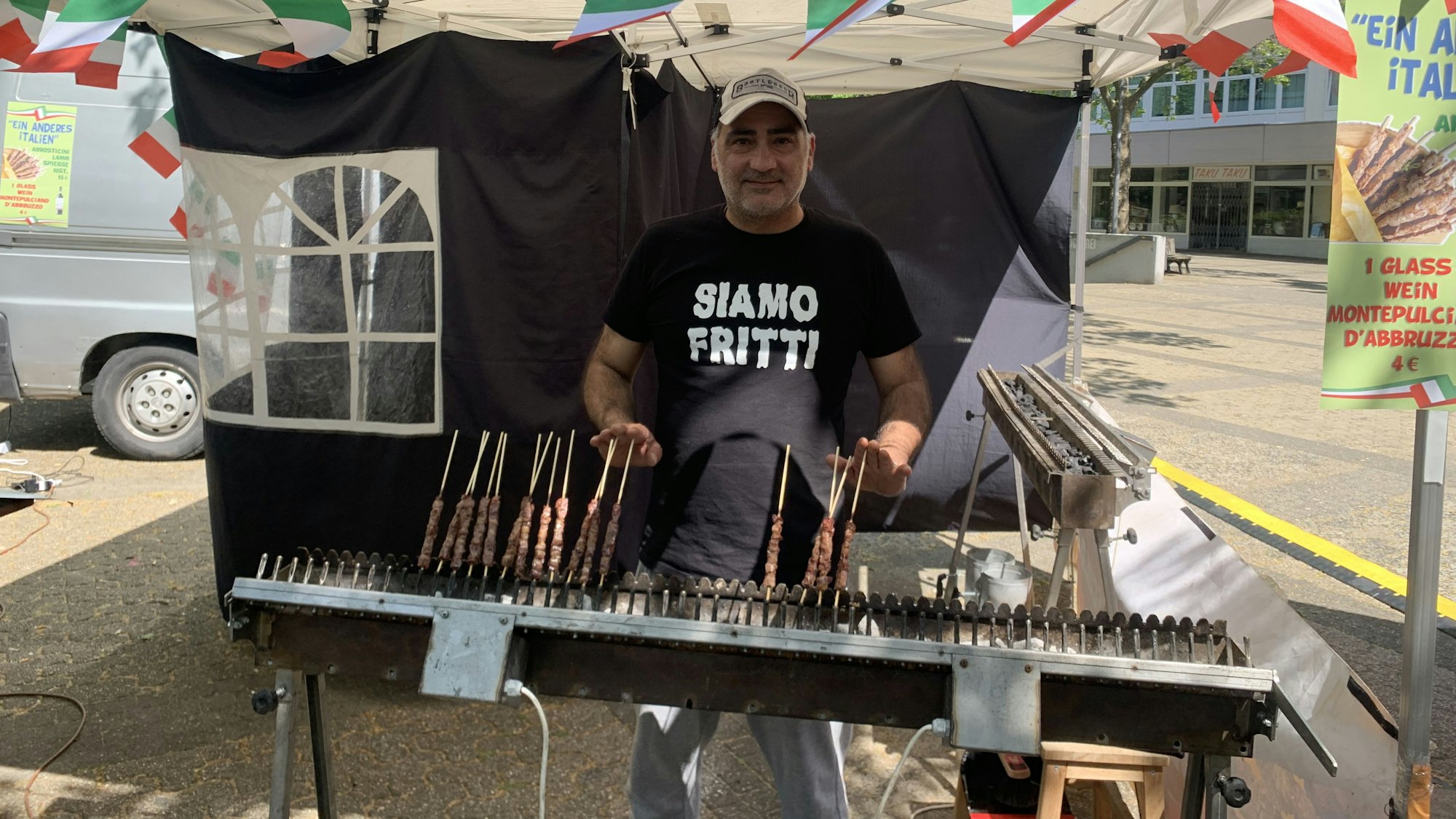 Auf dem Foto ist ein Mann zu sehen, der auf einem Grill Fleischspieße zubereitet.