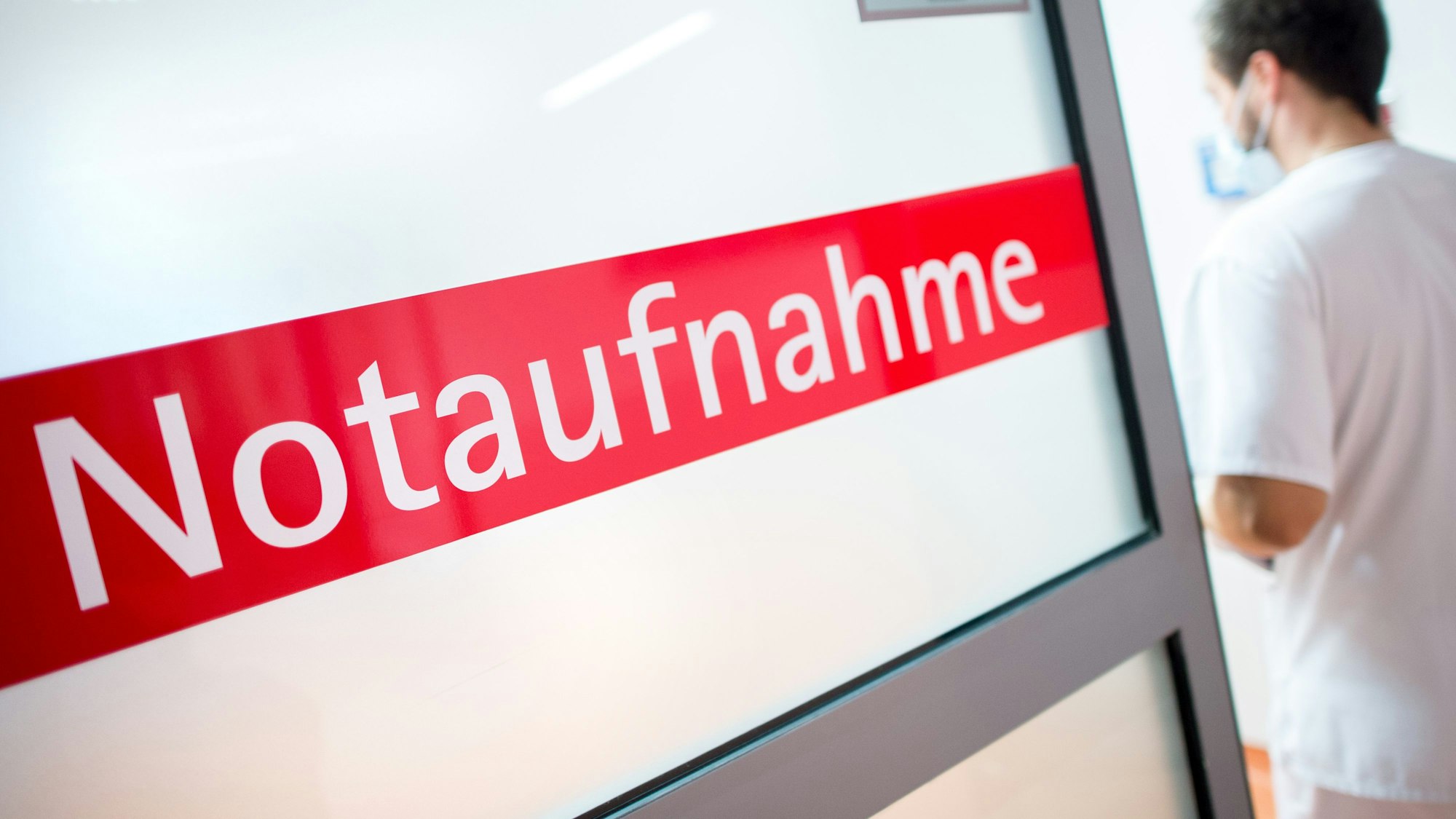 Ein Krankenpfleger tritt durch eine Glastür mit der Aufschrift "Notaufnahme".