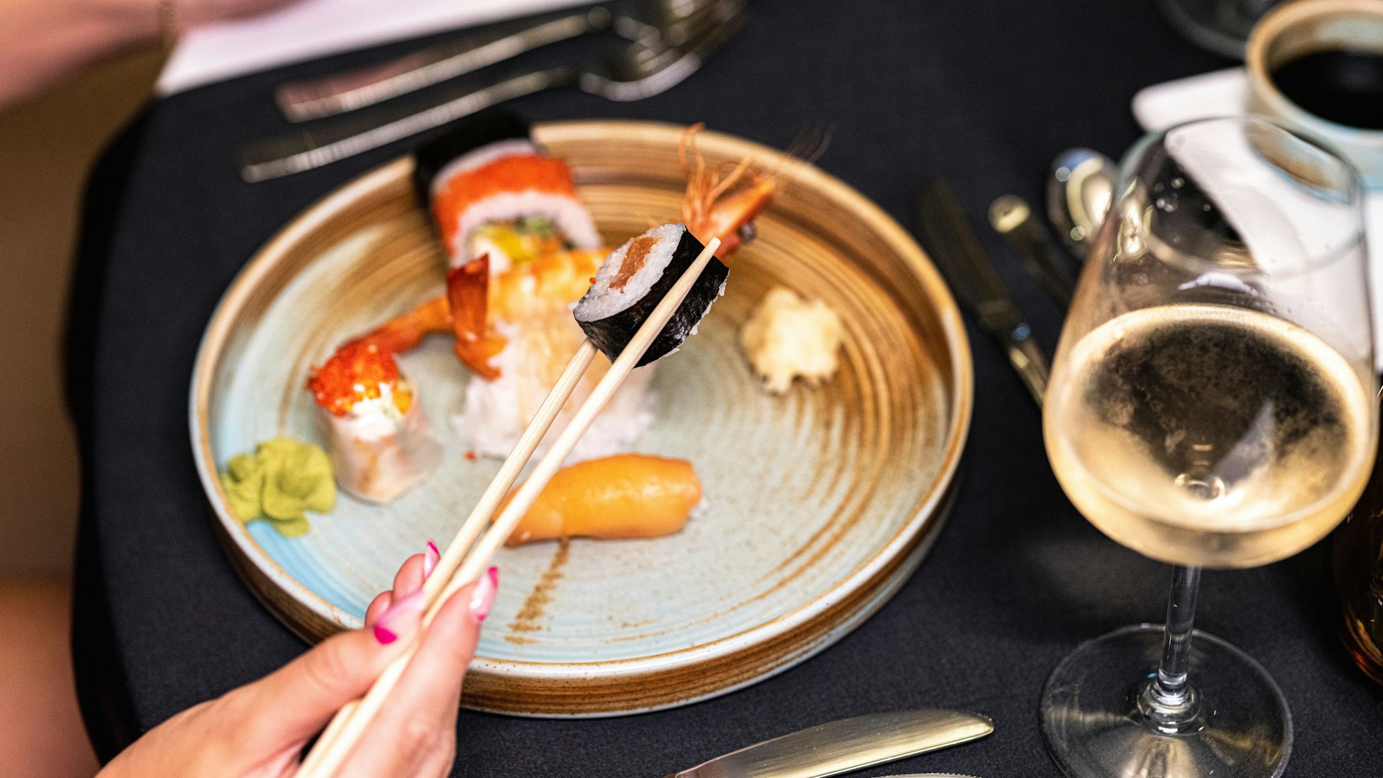 Eine Frau hält ein Stück Sushi.