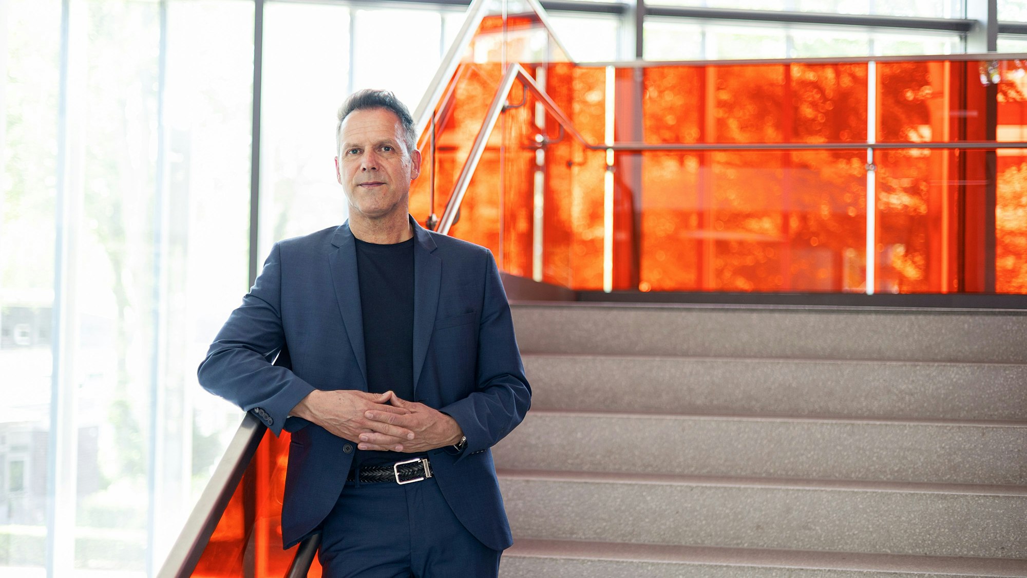 Ein Mann steht auf einer Treppe und schaut in die Kamera.