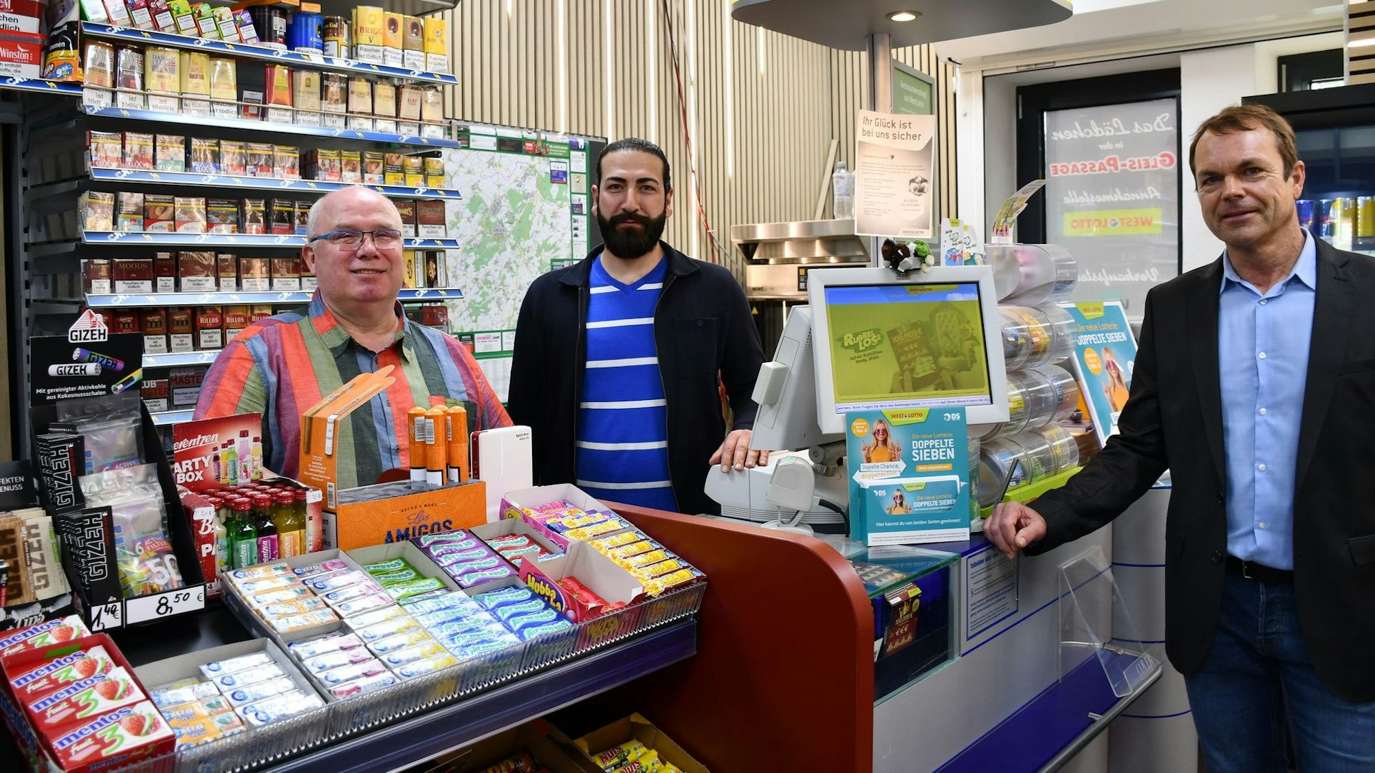 Im Bahnhofskiosk stehen Mohammed Albakkour (M.), Thorsten Oehmigen (l.) und Unternehmer Christof Schäfer.