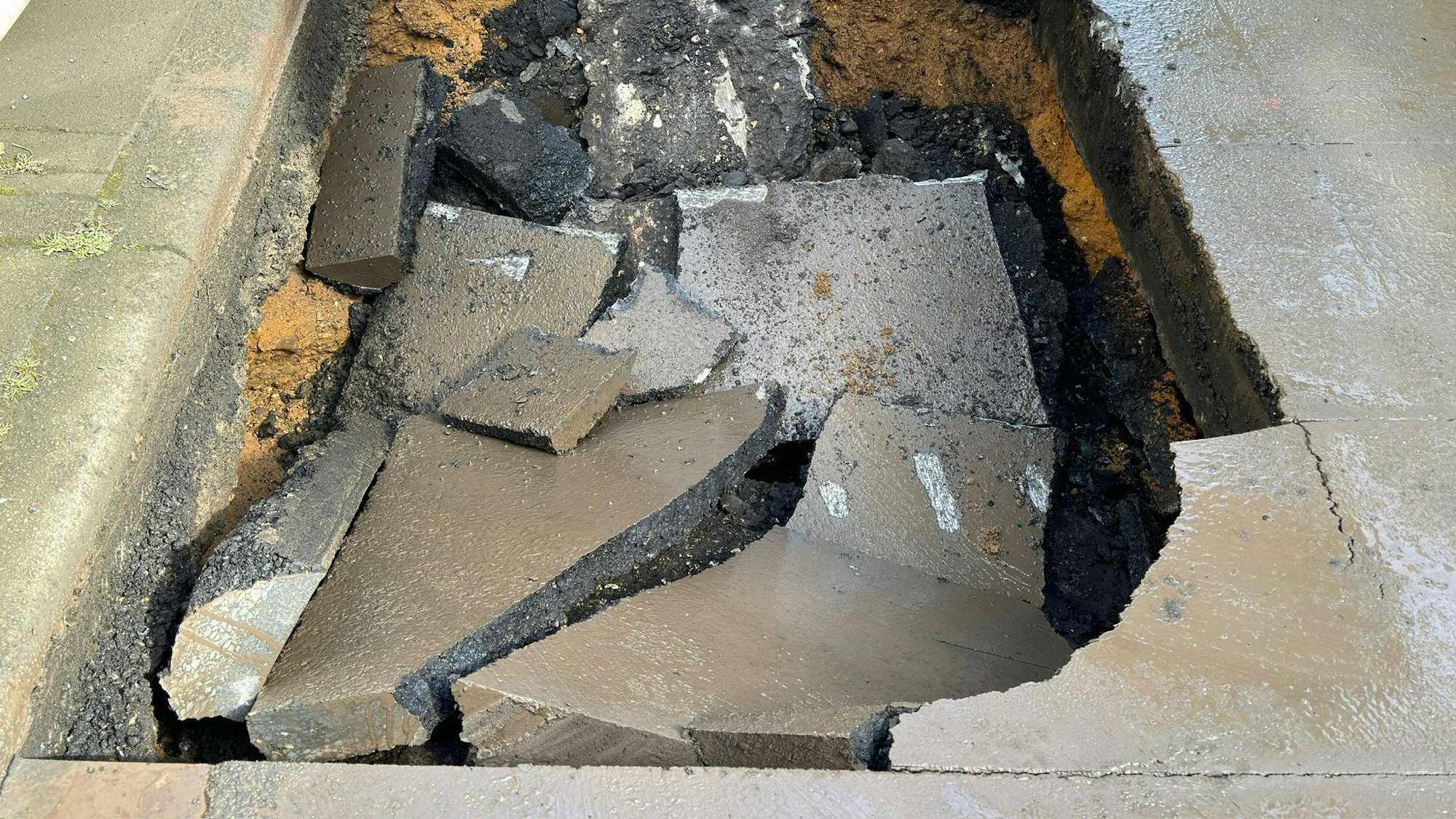 Auf dem Bild ist ein abgesackter Teil einer Strasse zu sehen.