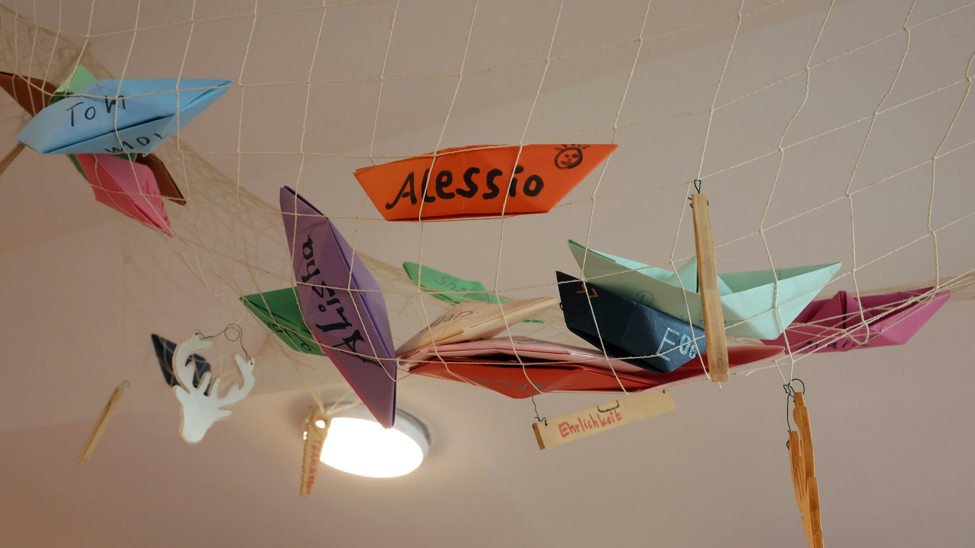 Ein Netz mit selbst gebastelten bunten Papierschiffchen mit Kindernamen