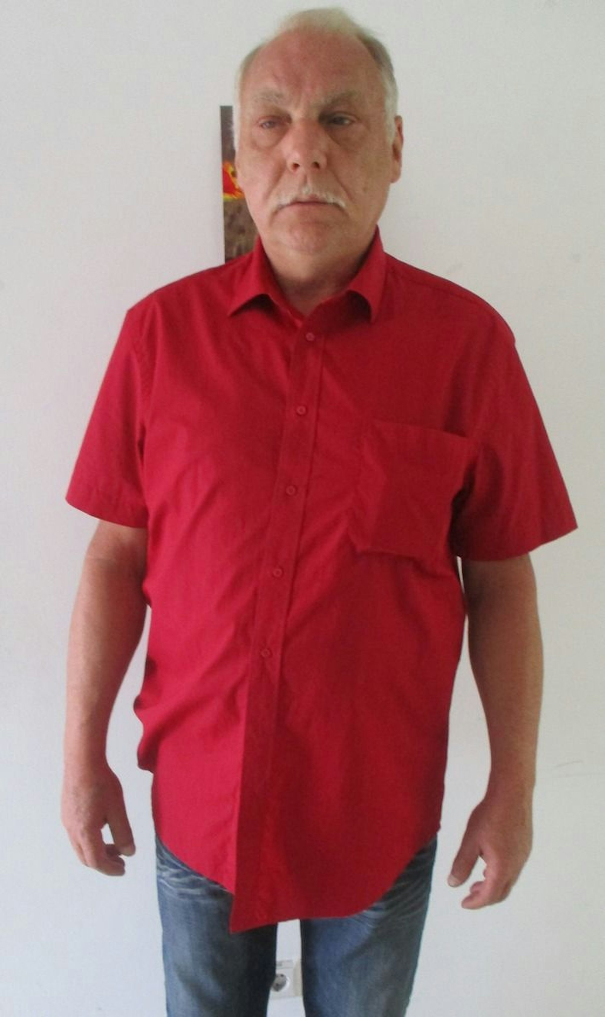 Aktuelles Foto eines gesuchten Mannes in einem roten Hemd und blauer Jeans.