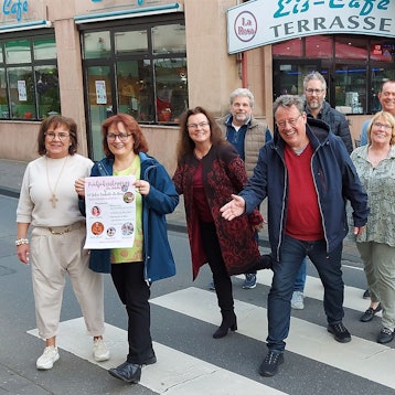Zahlreiche Männer und Frauen stehen auf einem Zebrastreifen in Mechernich. Sie machen Werbung für die Veranstaltung Rock am Rathaus, die am 25. Mai stattfindet.