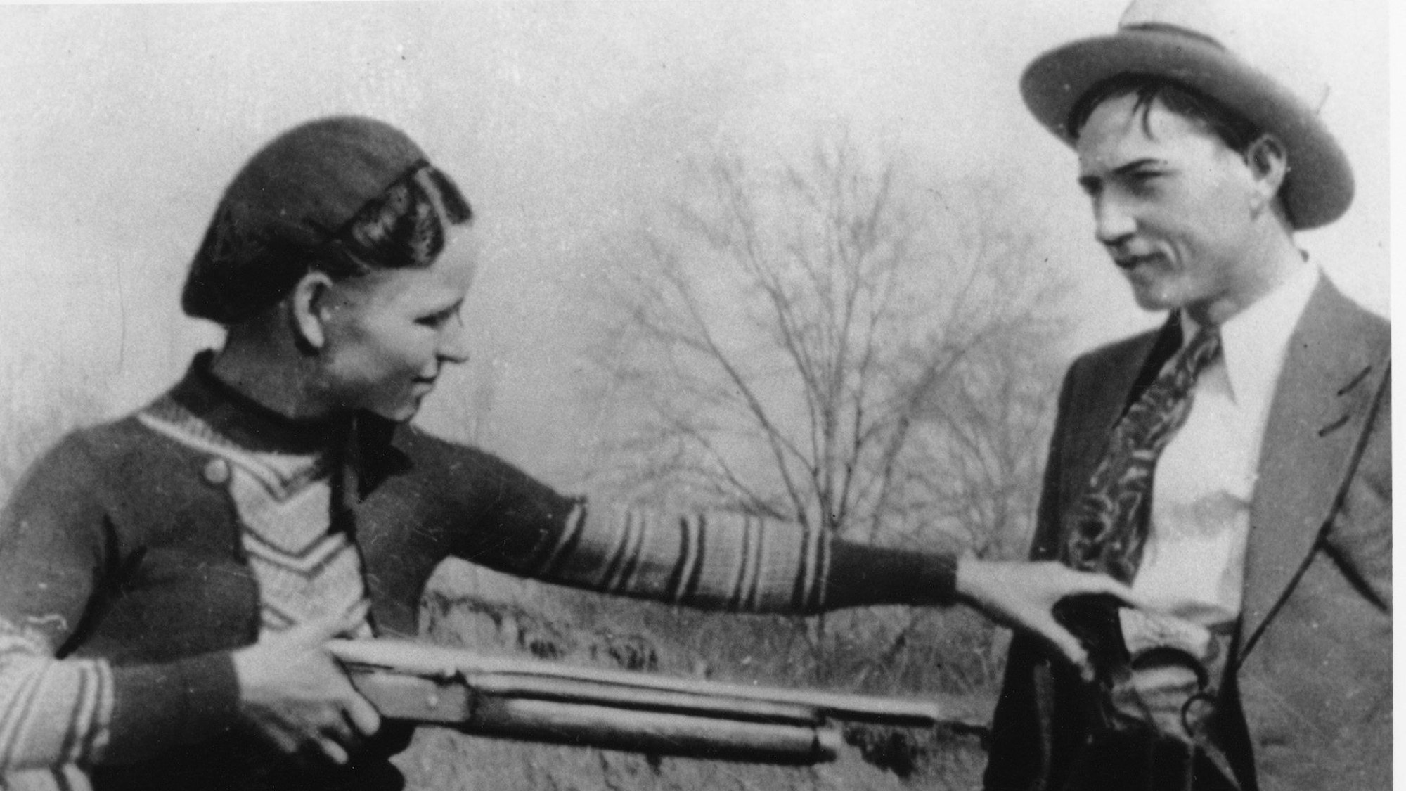 Auf einer Schwarz-Weiß-Aufnahme hält eine Frau ein Gewehr in Richtung eines Mannes. (Archivbild)