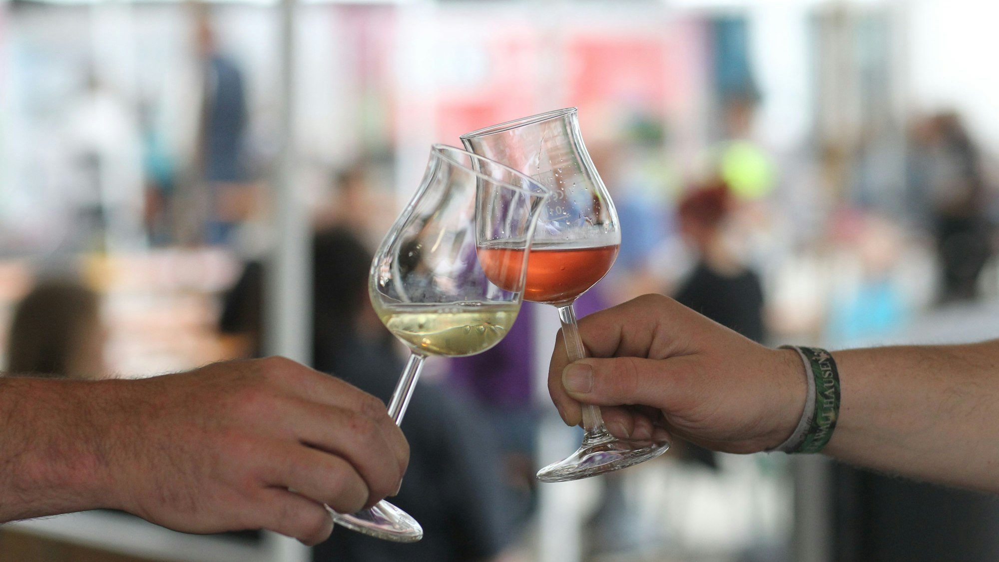 Zwei Menschen stoßen mit Weingläsern an.